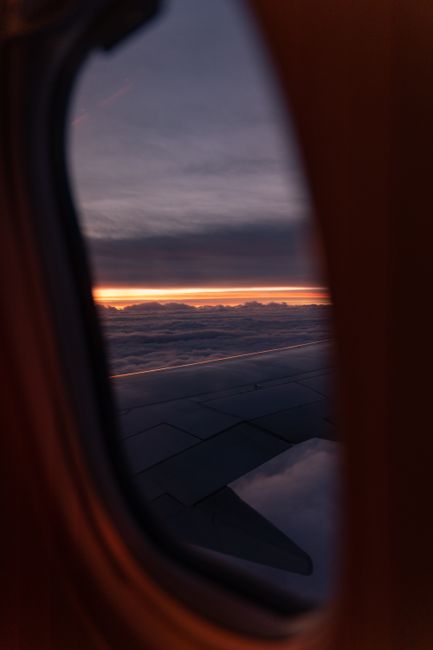 View from airplane window showing wings and sunset sky.