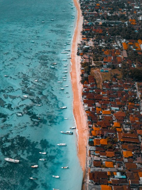 A scenic aerial view of the vibrant coast in Bali, showcasing the clear blue waters and nearby resorts.
