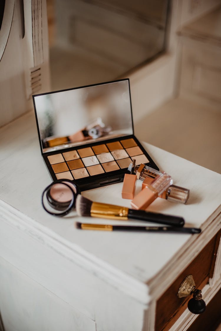 Assorted Cosmetic Products On White And Brown Wooden Drawer Cabinet