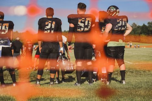 Free Football players in uniforms on a sunny day, seen from behind through an orange net. Stock Photo