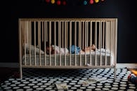 在灯光柔和的托儿所里，一个婴儿安静地睡在色彩缤纷、舒适的婴儿床中