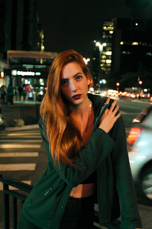 Photo of Woman Holding Her Shoulder While Standing by Sidewalk