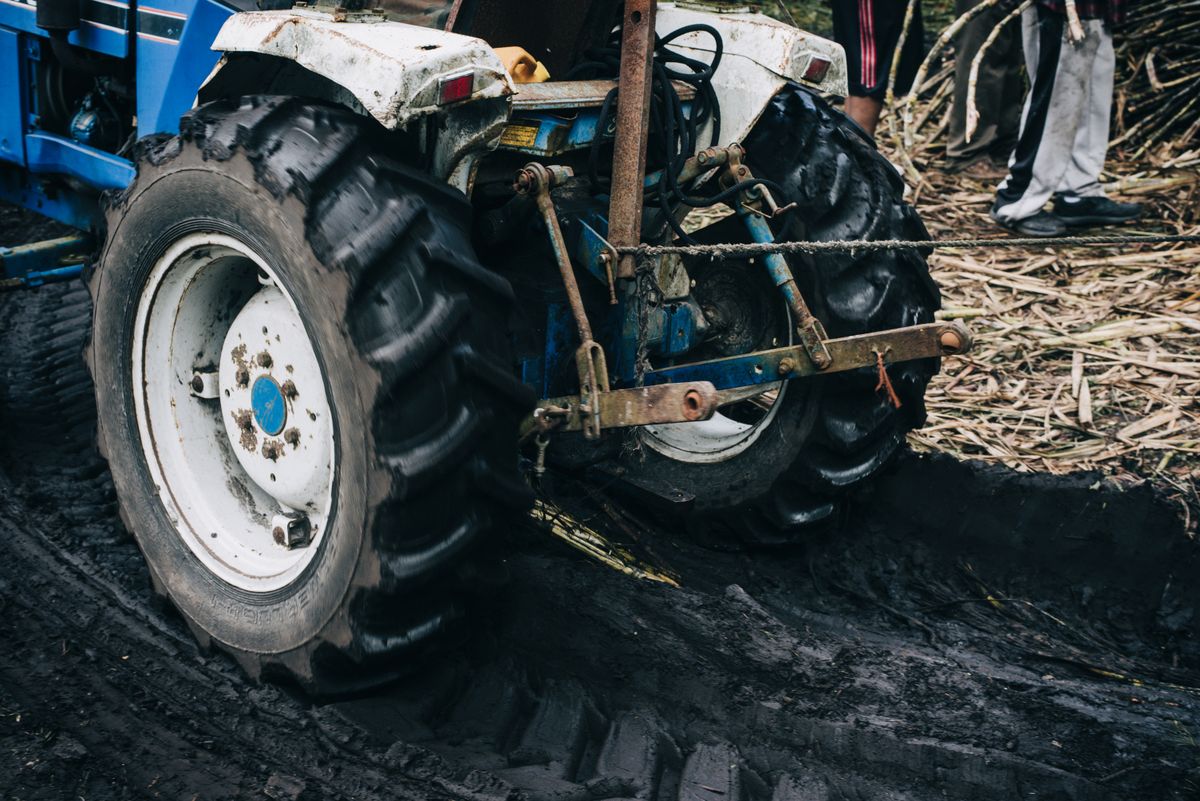 a mud-covered laptop resting on a tractor hood