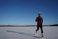 冬日里，一名男子在雪地上奔跑，头顶是晴朗的蓝天