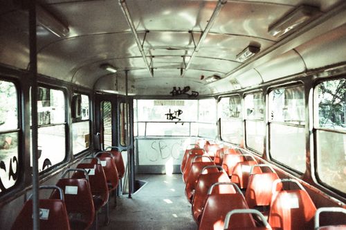 Free Retro bus interior with red seats and graffiti, evoking nostalgia in a sunny setting. Stock Photo