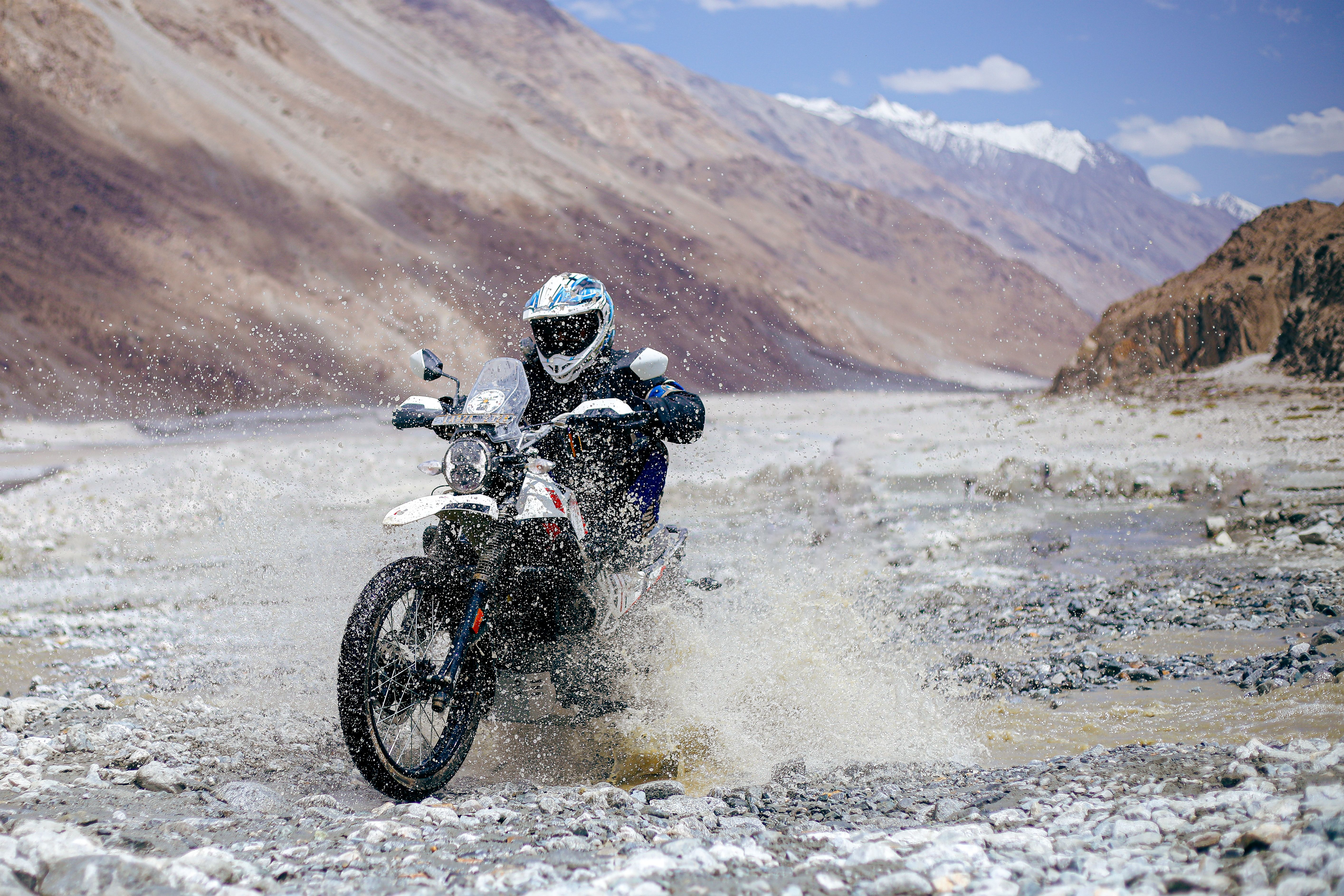 A person riding a motorcycle through a rocky area · Free Stock Photo