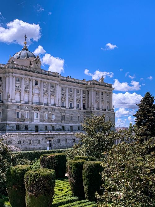 Free Stunning view of the Royal Palace of Madrid with blue sky and lush gardens. Stock Photo