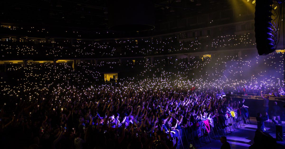 A packed indoor concert with audience lights creating a stunning visual display.