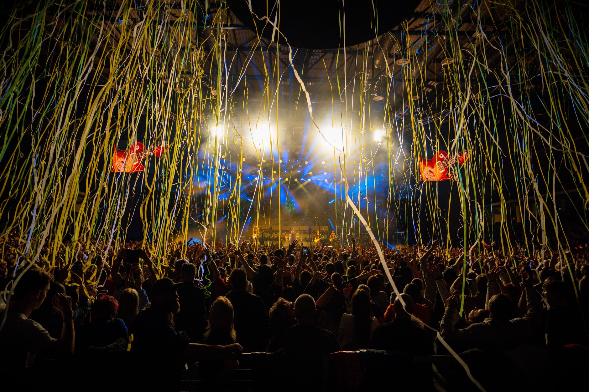 Dynamic concert scene with audience, vibrant lights, and cascading confetti. Captures the energy and excitement of live music.