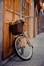 一辆迷人的老式自行车和一个装满鲜花的篮子，停靠在鹅卵石街道旁一扇华丽的木制门边