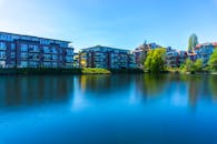 清澈的蓝天下，平静的河流映衬着现代公寓楼的宁静景色