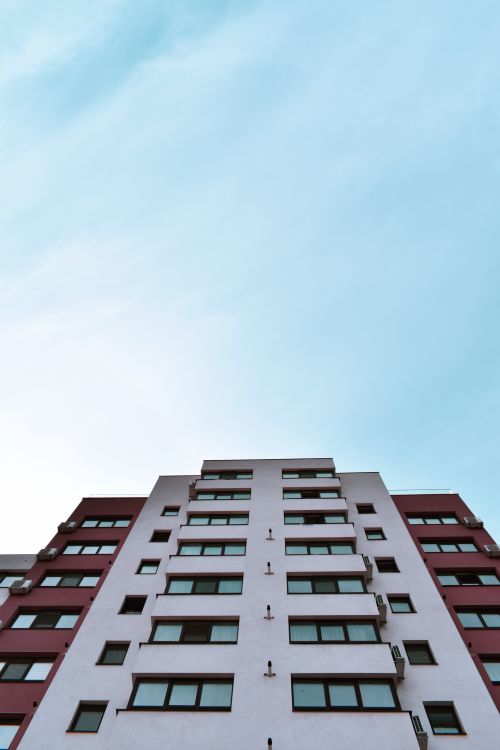 Free A low-angle view of a modern high-rise building under a clear blue sky. Stock Photo