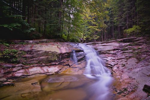 Free Peaceful waterfall amidst autumn forest rocks, perfect for nature enthusiasts. Stock Photo