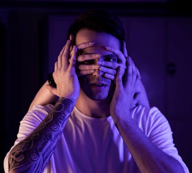 紫色灯光下，一位手臂有纹身的男模特，用多只手遮住了脸