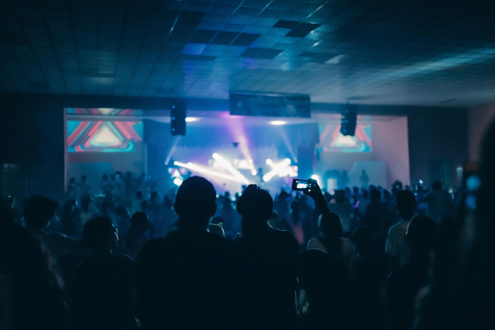 Vibrant indoor concert scene with a crowd enjoying live performances under dynamic stage lighting.
