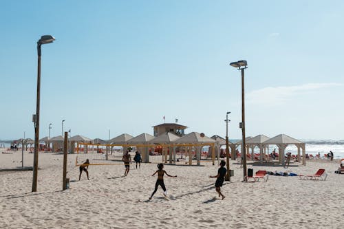 People Playing Beach Volleyball Under Clear Blue Sky