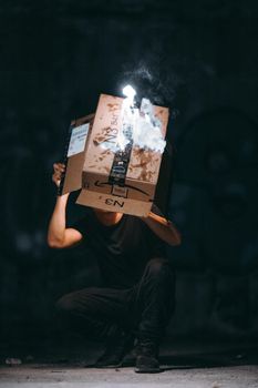黑暗中，一个人蹲着，手里拿着一个烟盒