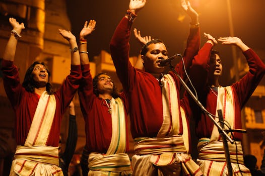 Group of men in traditional attire singing with raised hands in Varanasi, India.