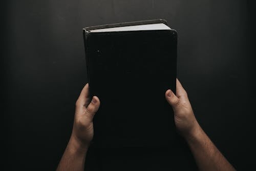 Free Person Holding Black Cover Bible Stock Photo