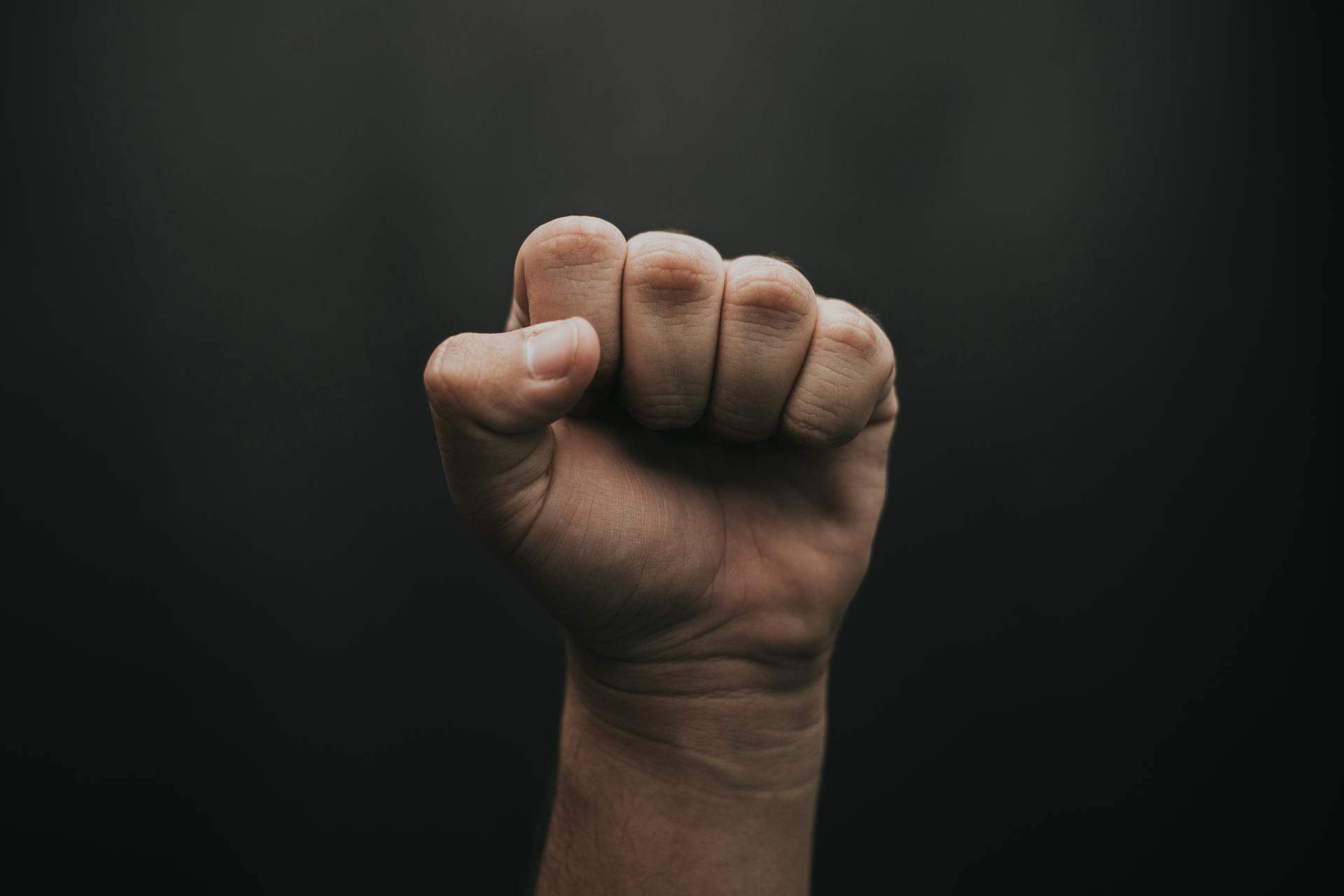 A close-up of a fist raised against a dark background, symbolizing strength and unity.