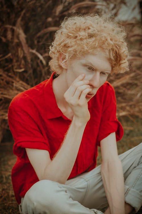 Uomo In Camicia Di Polo Rossa Che Si Siede Sulla Terra