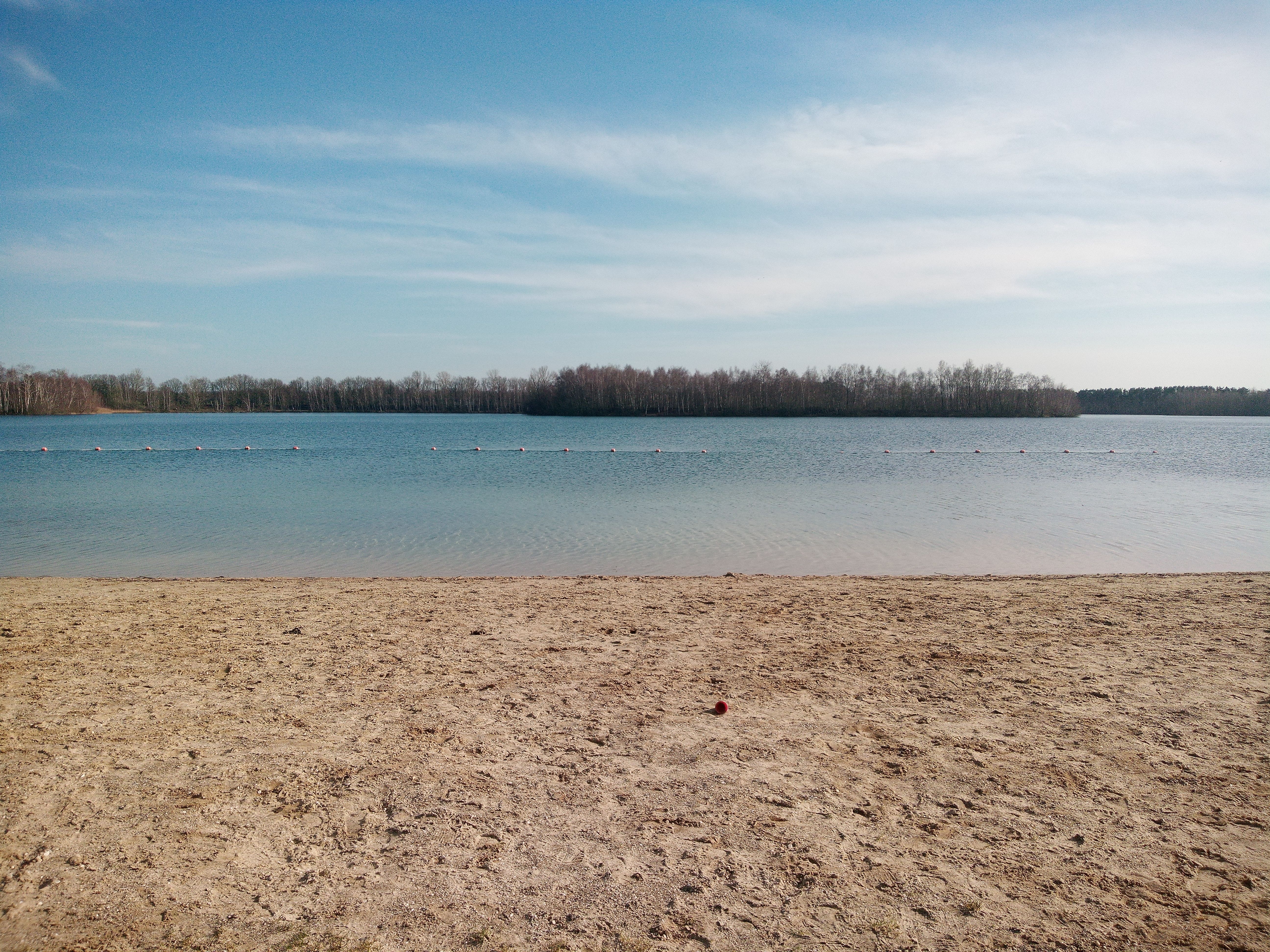 Peaceful sandy beach by the calm lake with clear blue skies in Langenboom, Netherlands.