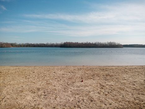 Peaceful sandy beach by the calm lake with clear blue skies in Langenboom, Netherlands.