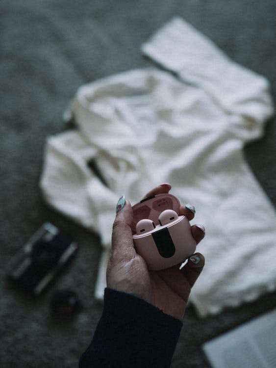 A person holding a pink airpods in their hand