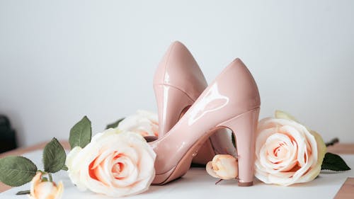 A pair of pink heels and roses on a table