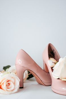 Soft pink high heels paired with roses, perfect for bridal fashion or decor inspiration.