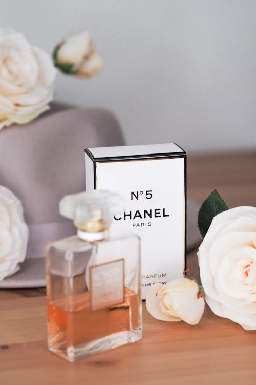 Chanel perfume bottle with flowers and hat on table