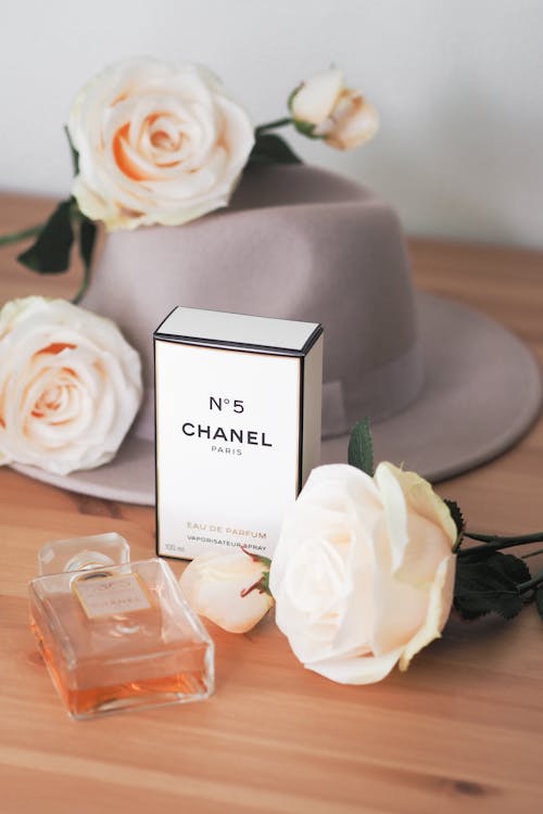 A bottle of chanel perfume sitting on a table next to roses