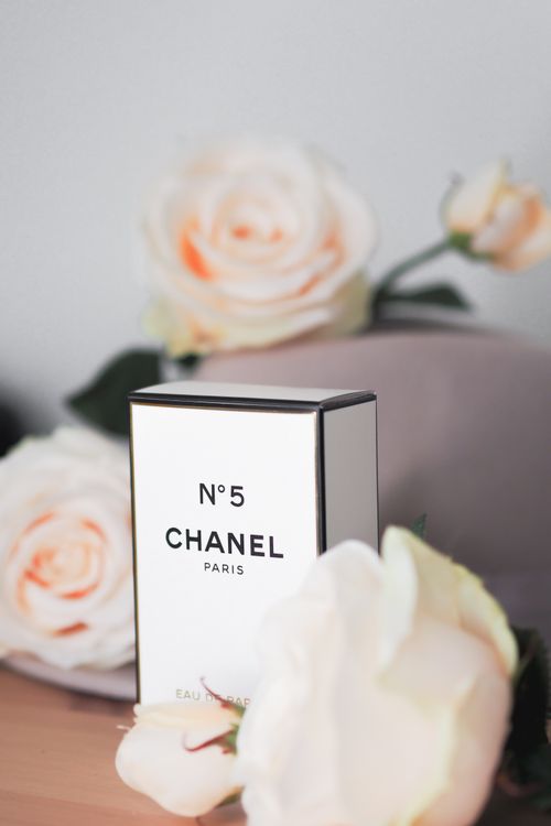 Free Chanel No. 5 perfume box surrounded by delicate white roses in a soft focus setting. Stock Photo