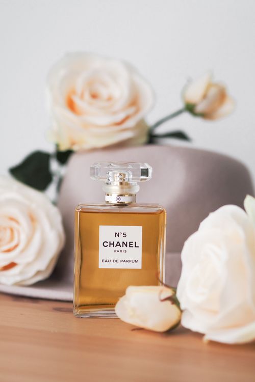 Free Chanel No.5 perfume surrounded by delicate roses, showcasing elegance and luxury. Stock Photo