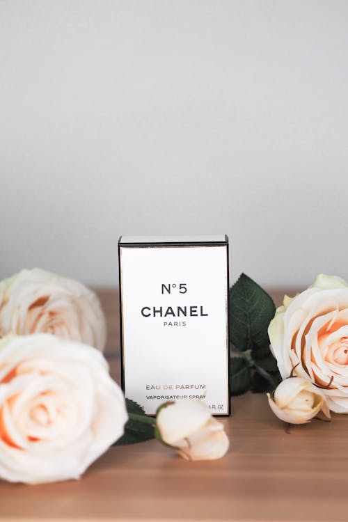 A bottle of chanel perfume sitting on a table with roses