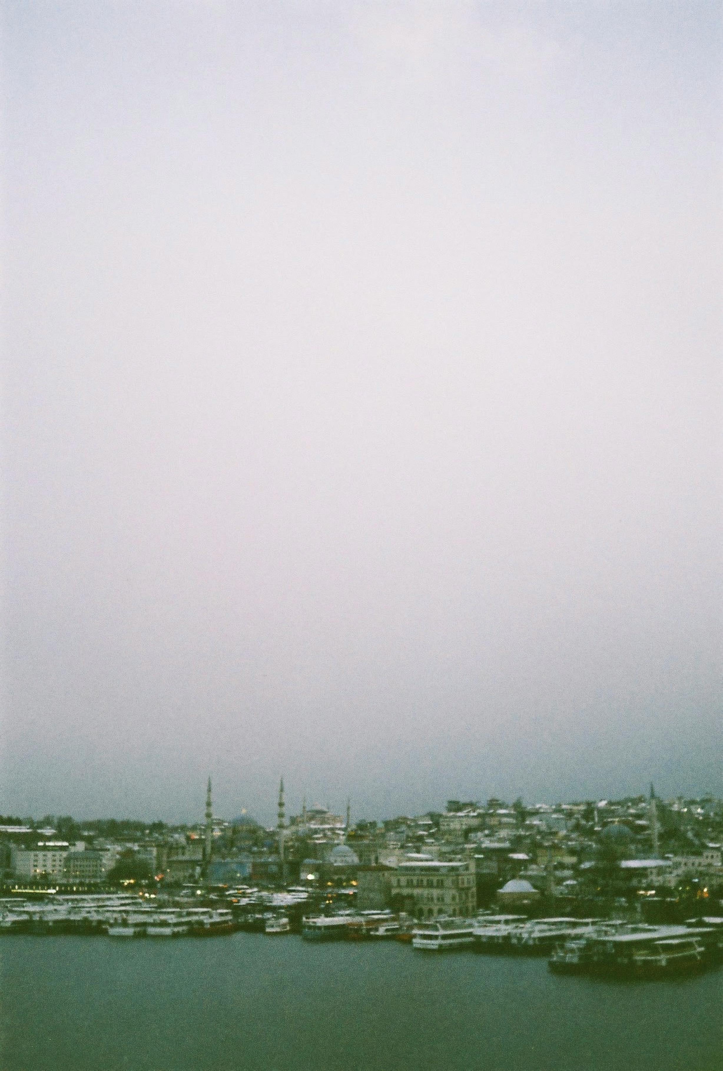 A serene view of Istanbul's waterfront with a cityscape backdrop under a cloudy sky.