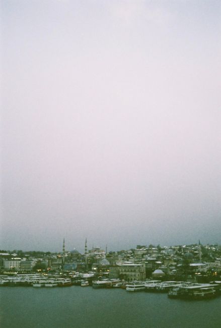 A serene view of Istanbul's waterfront with a cityscape backdrop under a cloudy sky.