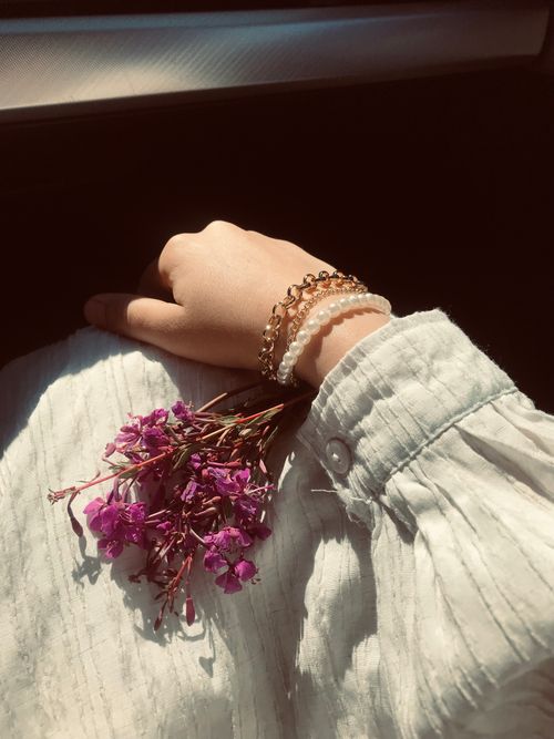 Free A woman's hand holds a bouquet of dried purple flowers in sunlight, showcasing delicate jewelry. Stock Photo