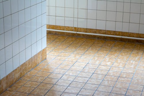 A bathroom floor with tiled tiles and a toilet