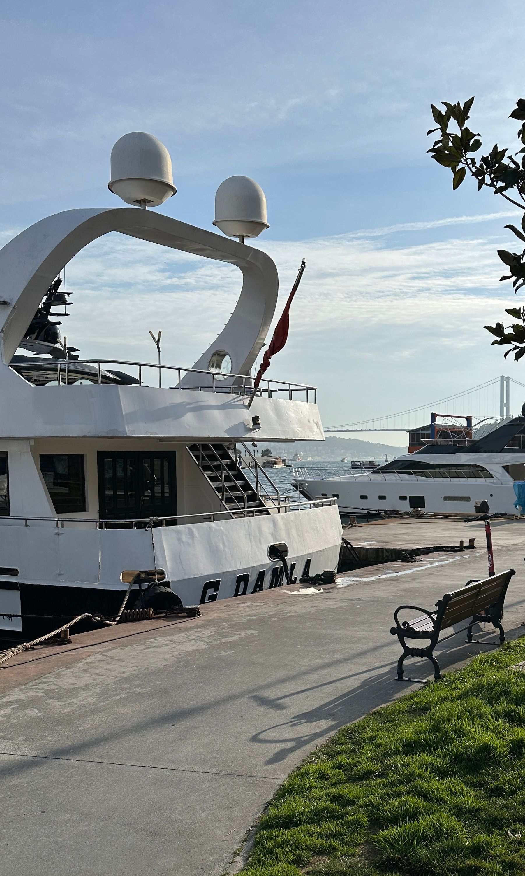 Elegant yachts docked in Istanbul with a clear blue sky and Bosphorus Bridge in the background.