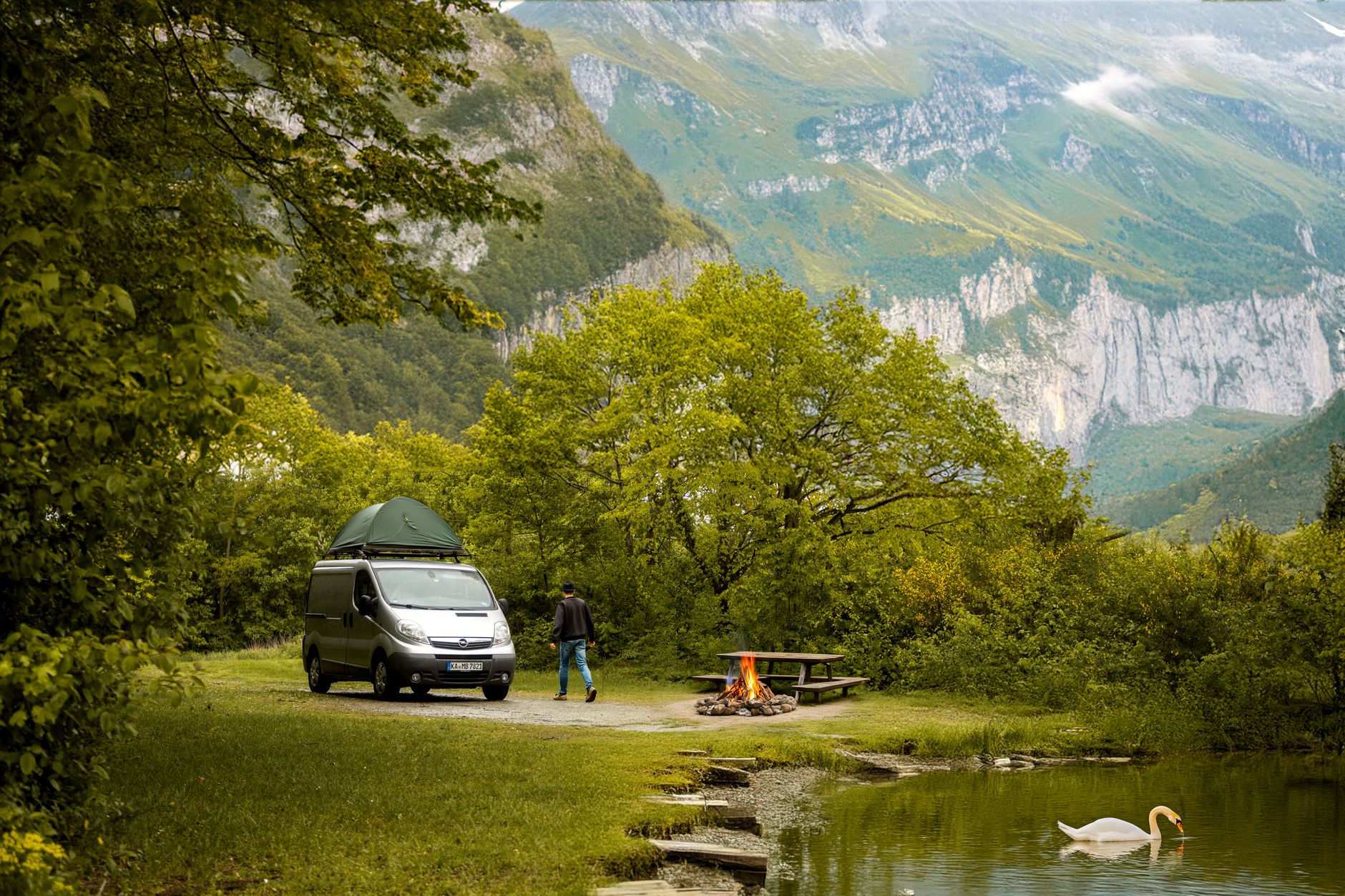 A serene camping scene with a van by a mountain lake, perfect for travel enthusiasts.