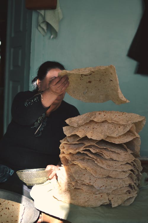A woman is making a stack of flat bread
