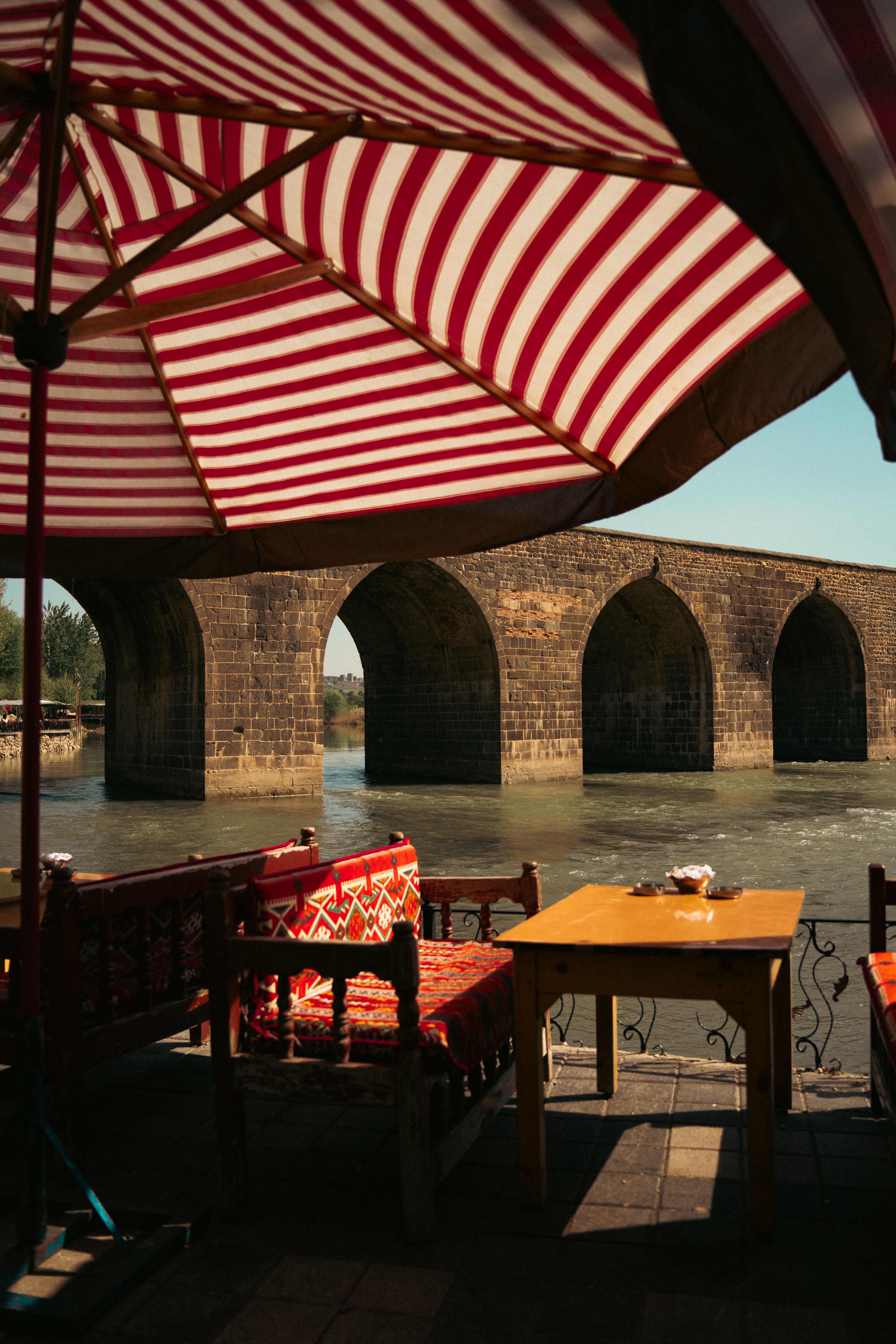 Charming Riverside Cafe with Historic Stone Bridge View · Free Stock Photo