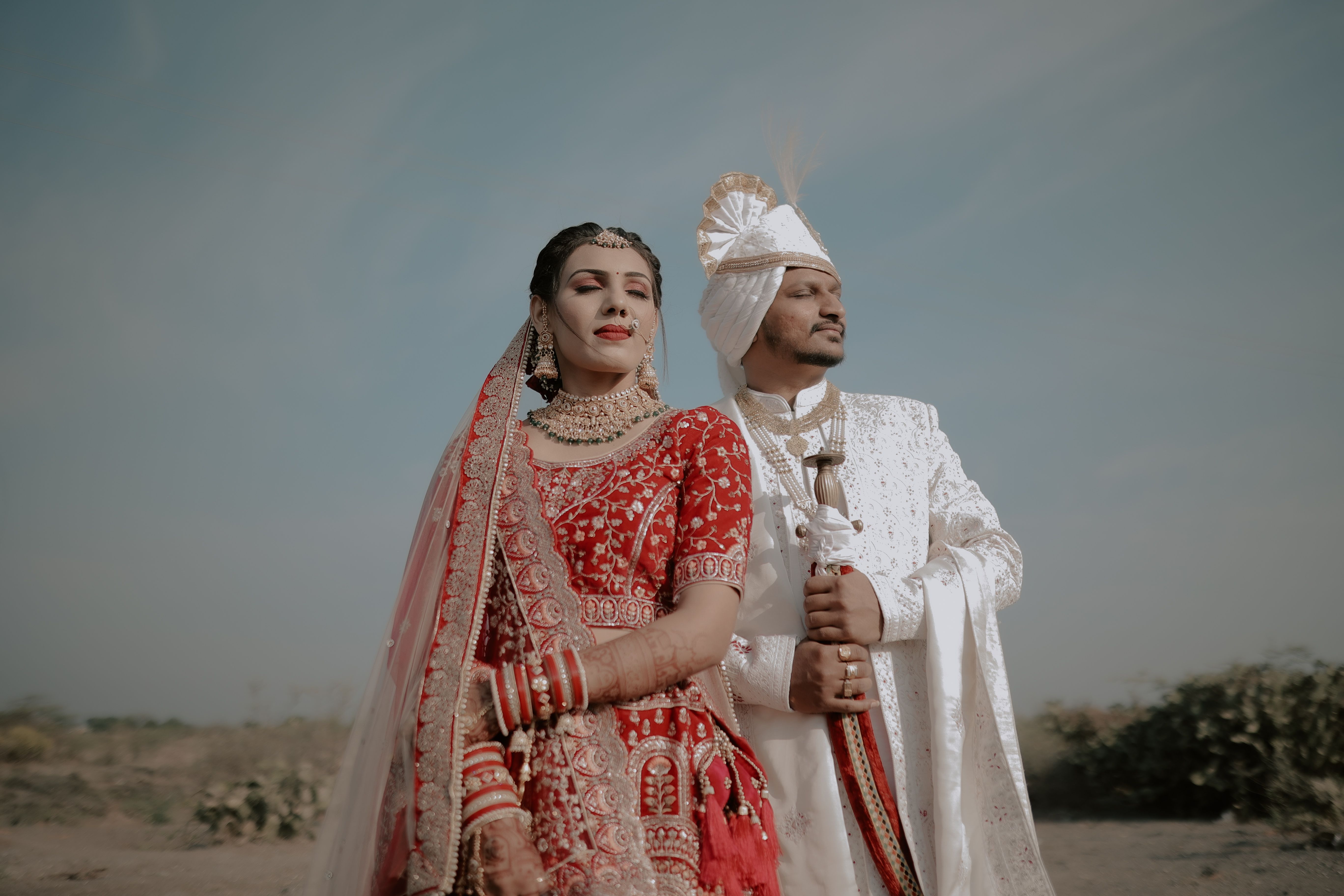 Stunning outdoor portrait of a couple in traditional Indian wedding attire, showcasing vibrant cultural elegance.