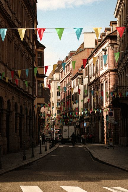 Charming urban street in Strasbourg, France with colorful decorations and historic buildings.