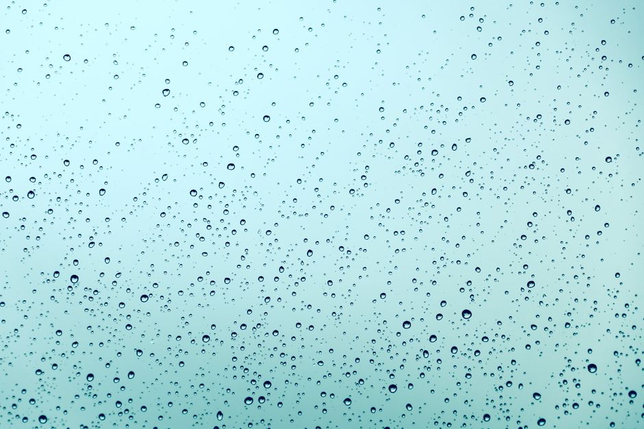 A serene abstract view of water droplets scattered across a smooth glass surface, expressing tranquility.