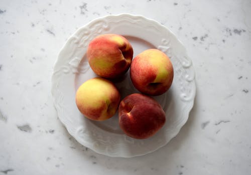 Free Delicious peaches arranged on a decorative plate, showcasing freshness and natural beauty. Stock Photo