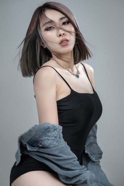 Elegant young woman in black bodysuit posing confidently in a studio shoot.