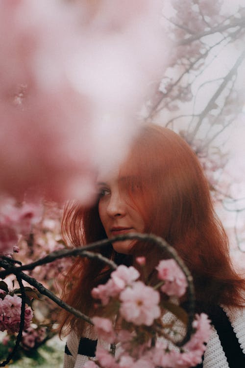 A woman with red hair and pink flowers in her hair