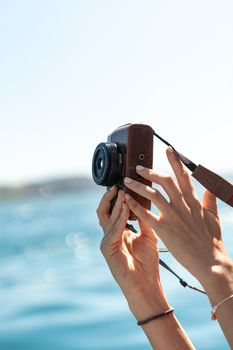 Hands holding a camera against the backdrop of the sea, capturing outdoor moments.